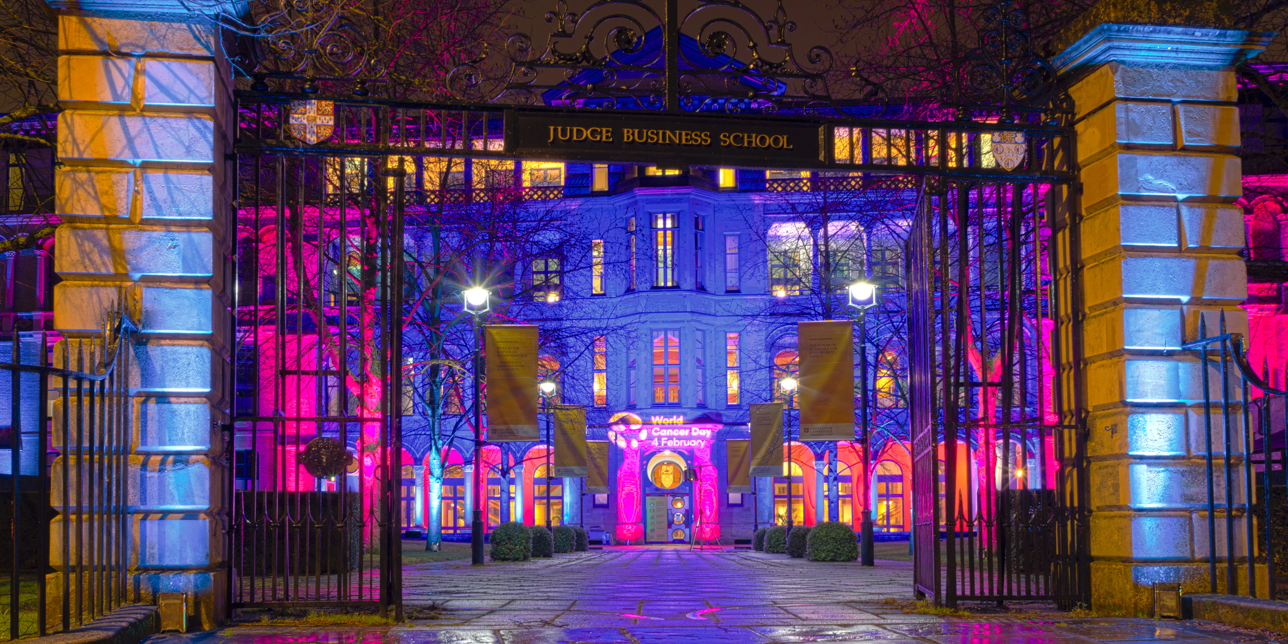 Cambridge Judge Business School illuminated in Cancer Research UK colours